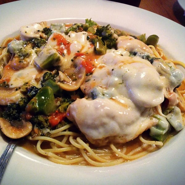 Spaghetti topped with melted cheese, broccoli, mushrooms, and red peppers in a light sauce.