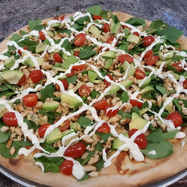 Frank's Pizza with chicken, spinach, avocado, cherry tomatoes, and a drizzle of white sauce.