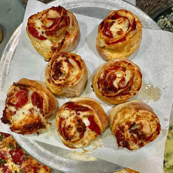 Seven Frank's Pizza pepperoni and cheese rolls on parchment paper, with a pizza slice visible.