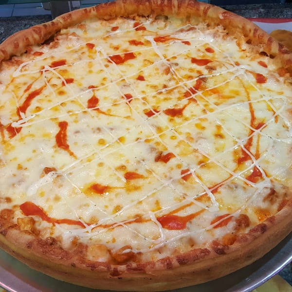 A Frank's Pizza & Italian Restaurant pizza, topped with melted cheese, red sauce, and white drizzle.
