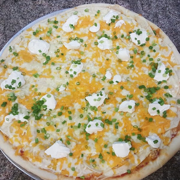 Frank's Pizza with melted cheese, dollops of sour cream, and chopped green onions.